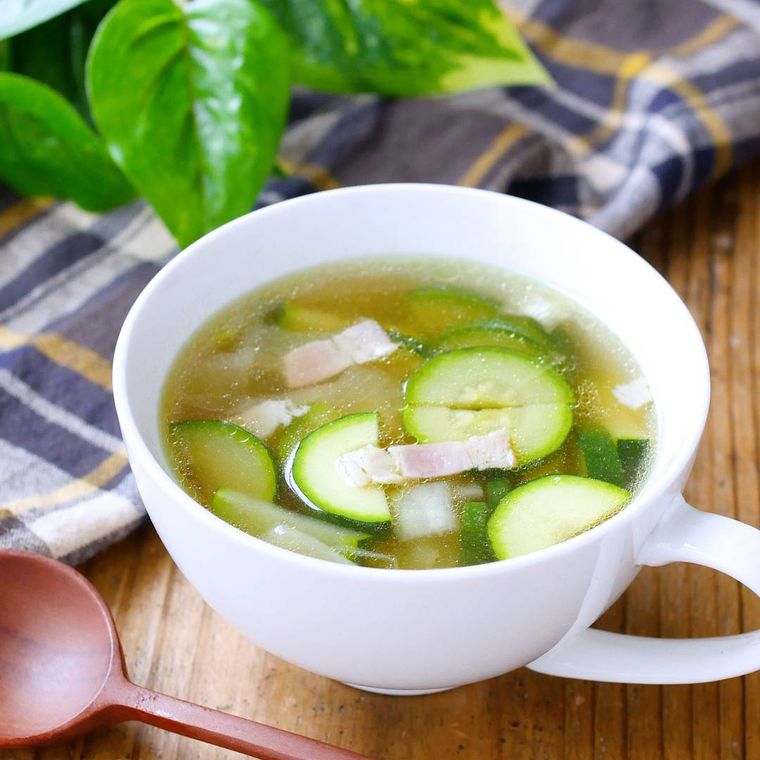 白いカップに盛りつけられたズッキーニと玉ねぎのコンソメスープ