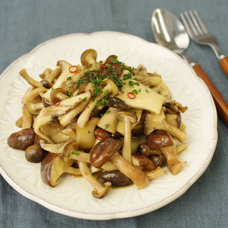 白い皿に盛りつけられたしめじやエリンギ、まいたけなどの炒め物