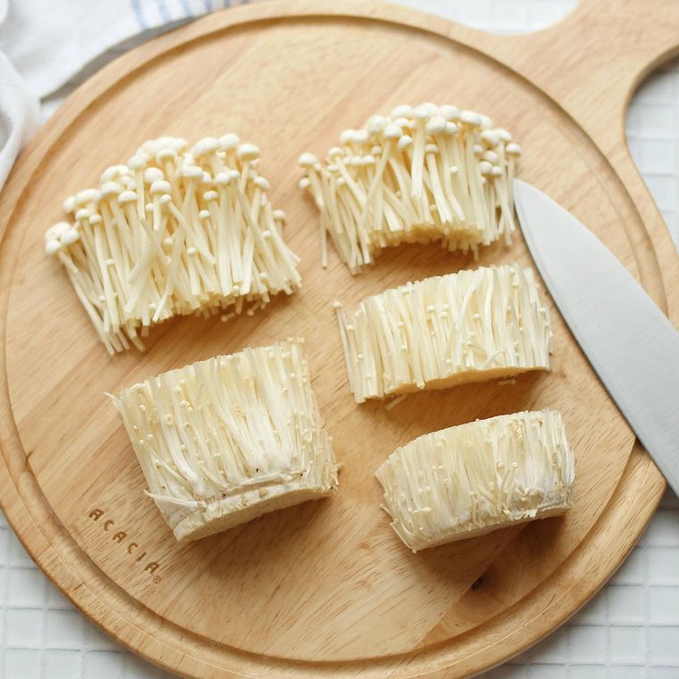 丸いカッティングボードの上で2等分と3等分にされたえのきだけ