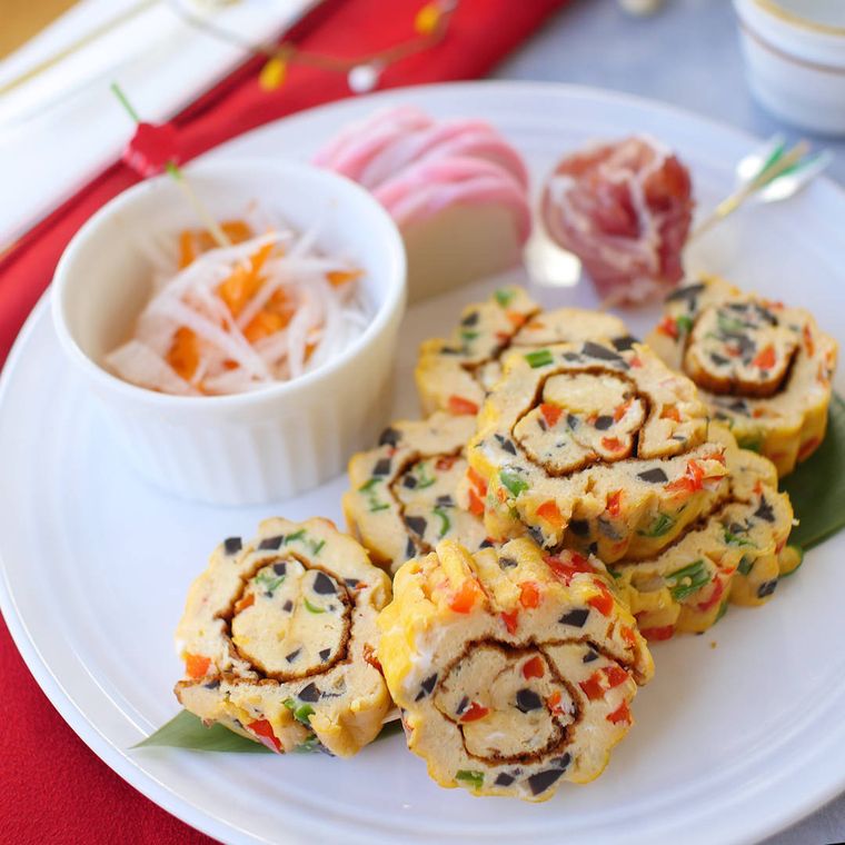 白い皿におせちの品々と並べられているくるくるオムレツ