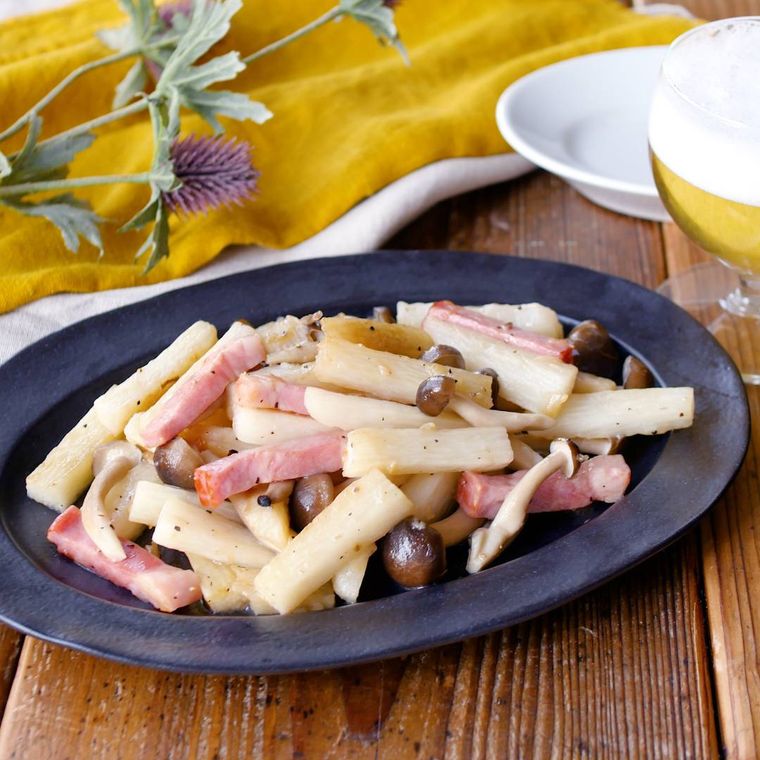 黒い皿に盛り付けられた山芋とベーコンのガーリック炒め