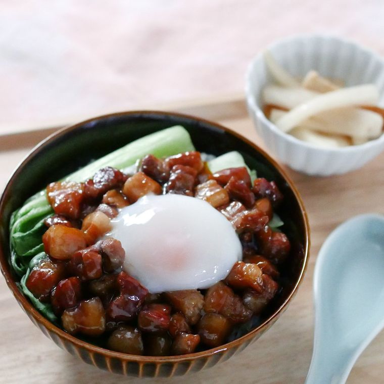 茶色い丼に盛り付けた、温泉卵とチンゲン菜が添えられているコロコロ豚バラ丼