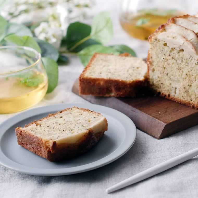 テーブルに置かれた、白い皿に盛られたりんごのパウンドケーキ