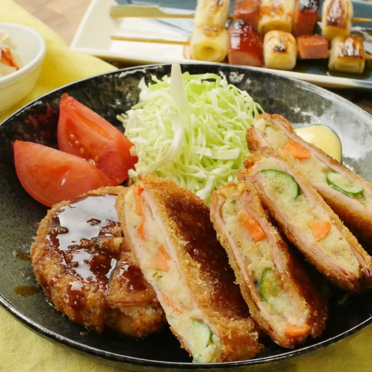 黒い皿にキャベツと盛られたポテトサラダハムカツ