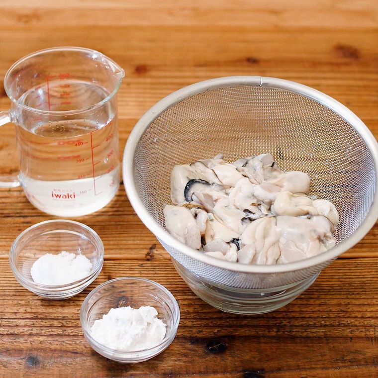 ステンレス製のざるに入っている生かきと水、塩、片栗粉
