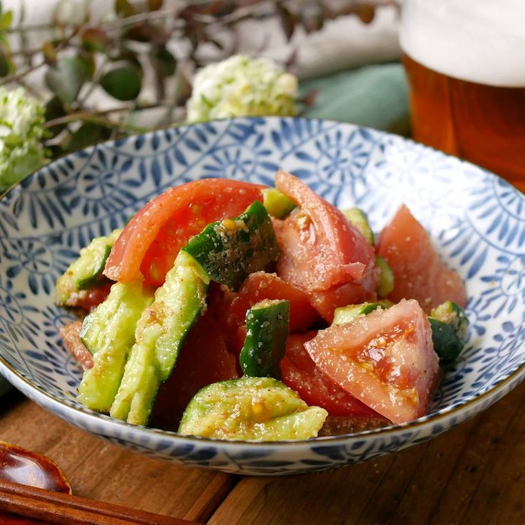 青い小皿に盛り付けられたトマトときゅうりのめんつゆ和え