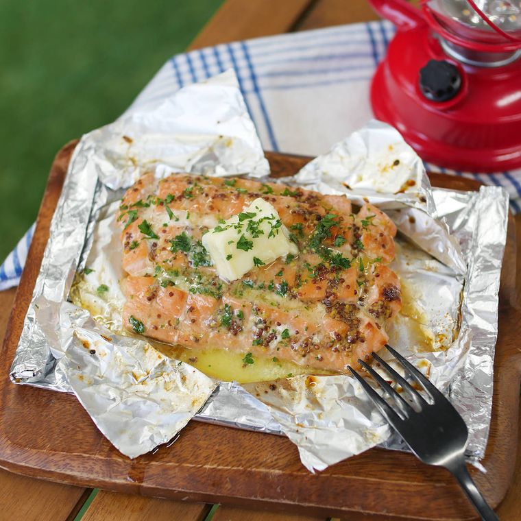 木製プレートに置かれた、ハニーガーリックサーモンのホイル焼きに、フォークが添えられている様子