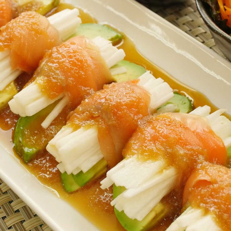 白い皿に盛り付けられた長芋とアボカドのスモークサーモン巻き