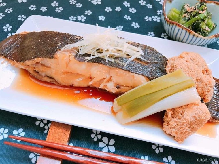 白い皿に盛られ、カレイの卵と長ねぎを添えたカレイの煮付け