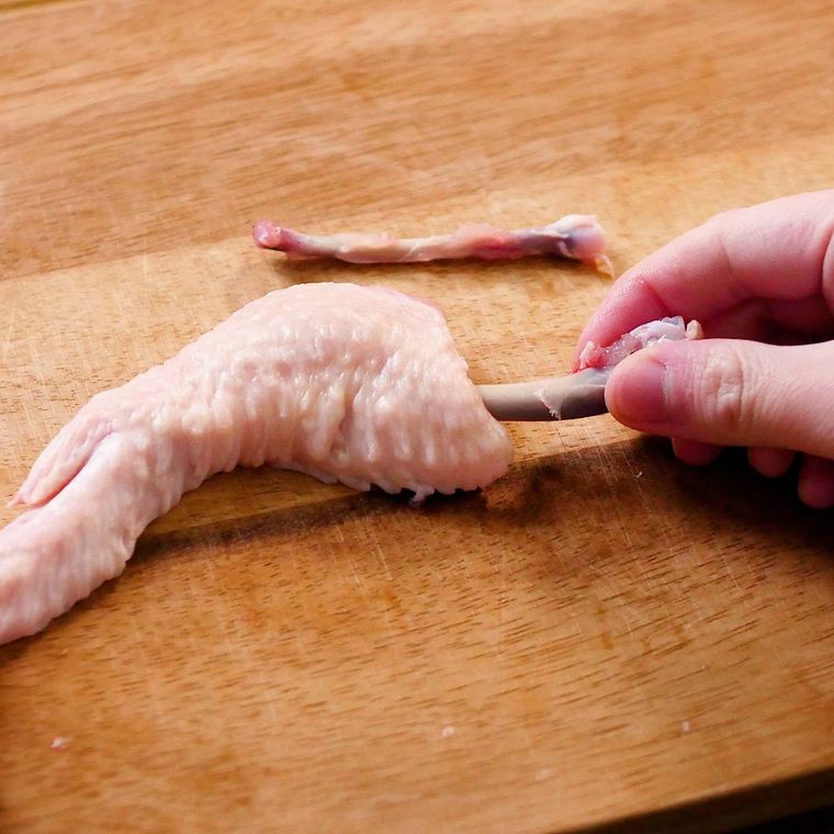 鶏手羽先の骨を肉から剥がしている様子