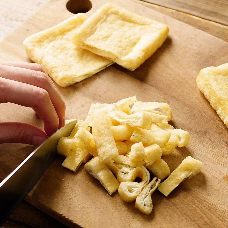 木製のまな板の上で短冊切りにされている油揚げ