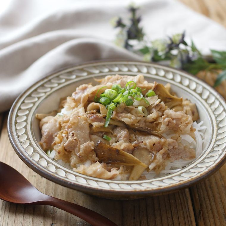 模様入りの皿に盛られている豚バラまいたけ丼