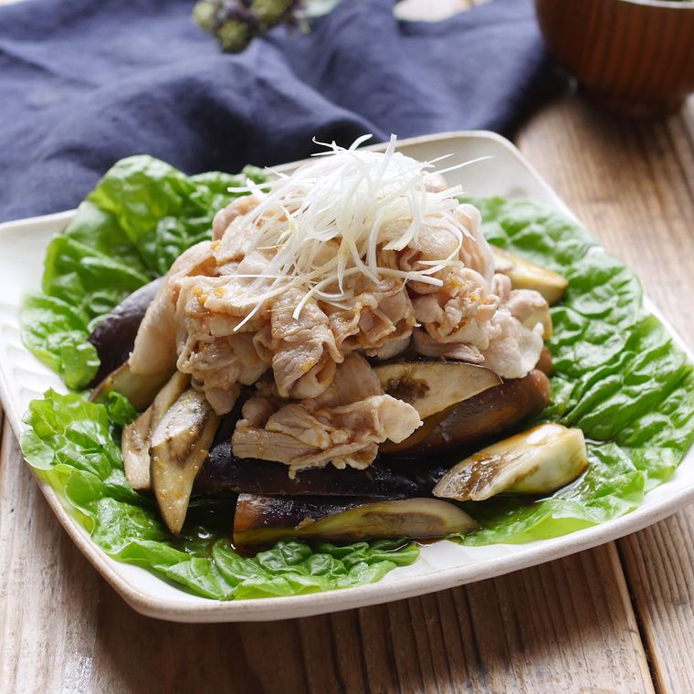 白い皿の上にあるレタスの上に盛られている豚肉となすのピリ辛サラダ