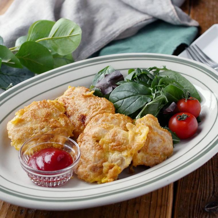 緑のライン入りの皿に盛られている鶏もも肉の粉チーズピカタ