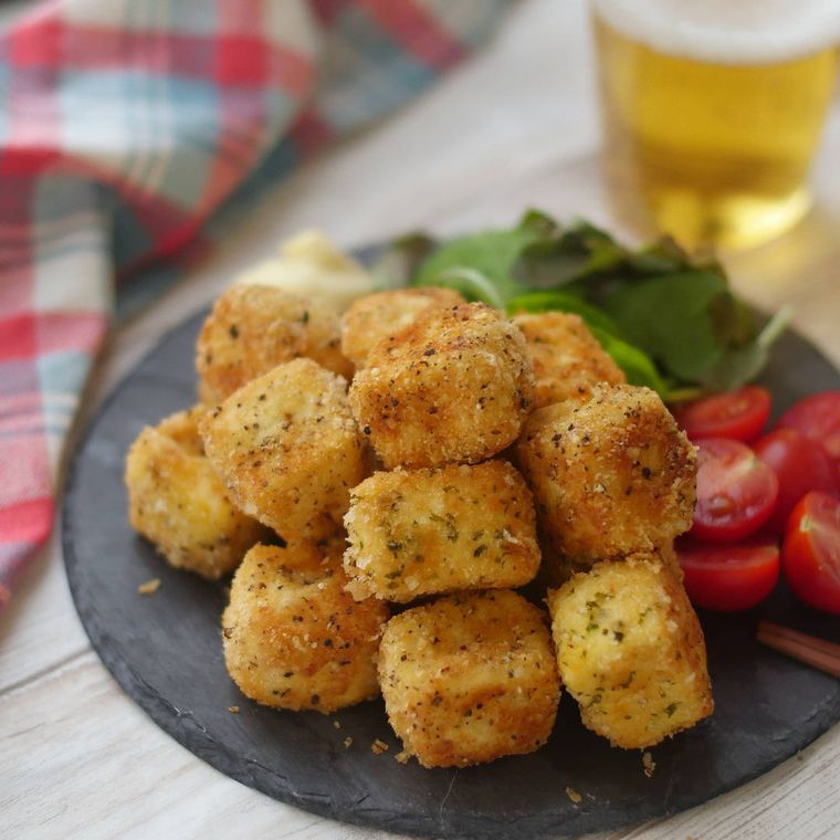 黒いプレート皿に盛られている豆腐の粉チーズフライ