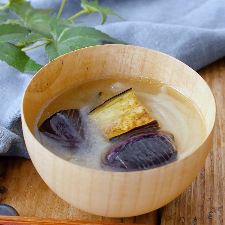 白木のお椀に盛りつけられている揚げなすと玉ねぎ入りの味噌汁