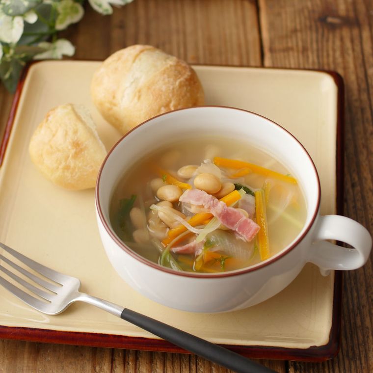 赤い縁取りのカップに盛りつけられた、大豆と水菜の和風スープ