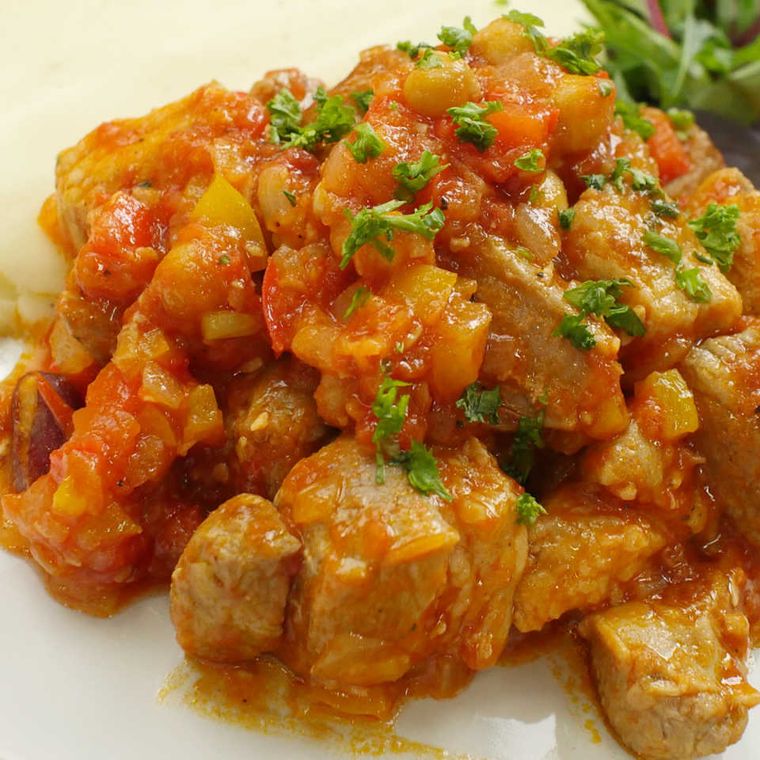 白い皿に盛りつけられた、豚バラ肉とパプリカのバスク風煮込み