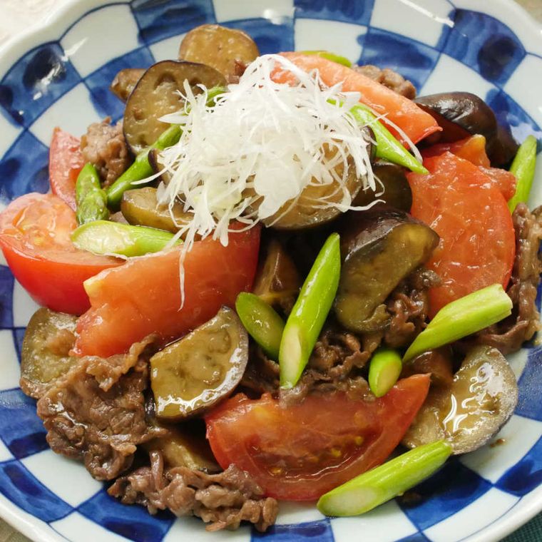 白地に青い柄が入った皿に盛り付けた薄切り牛肉とアスパラのオイスター炒め