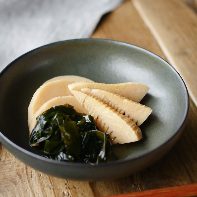 濃色の深皿に盛りつけられているたけのことわかめの若竹煮