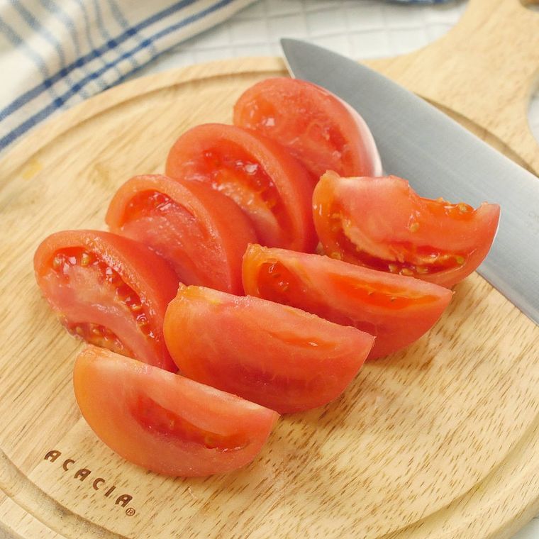 丸いカッティングボードの上でくし形切りされたトマト