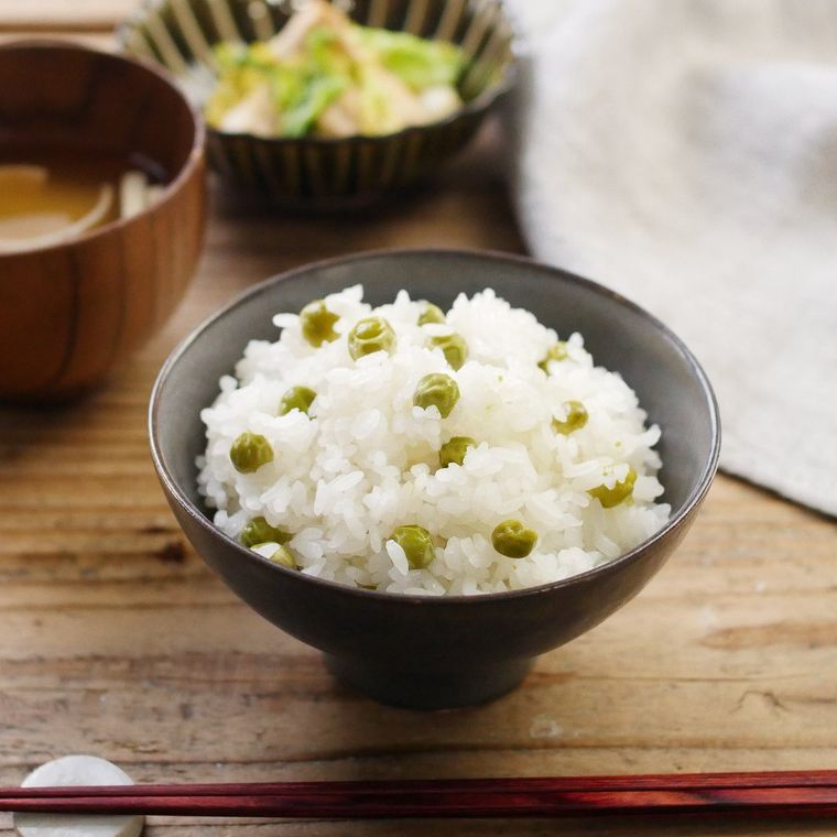 黒い茶碗に盛り付けたえんどう豆ごはん