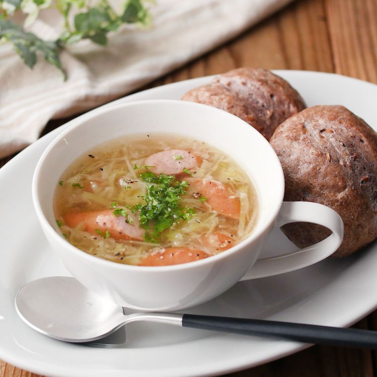 白いスープカップに入ったソーセージとキャベツのコンソメスープ