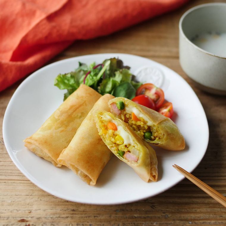 白い皿に盛り付けたソーセージ入りカレーピラフ春巻き