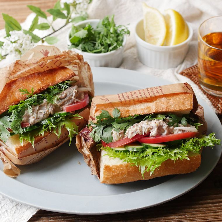 青い皿に盛りつけられたさばサンドにレモン、パクチーが添えられている