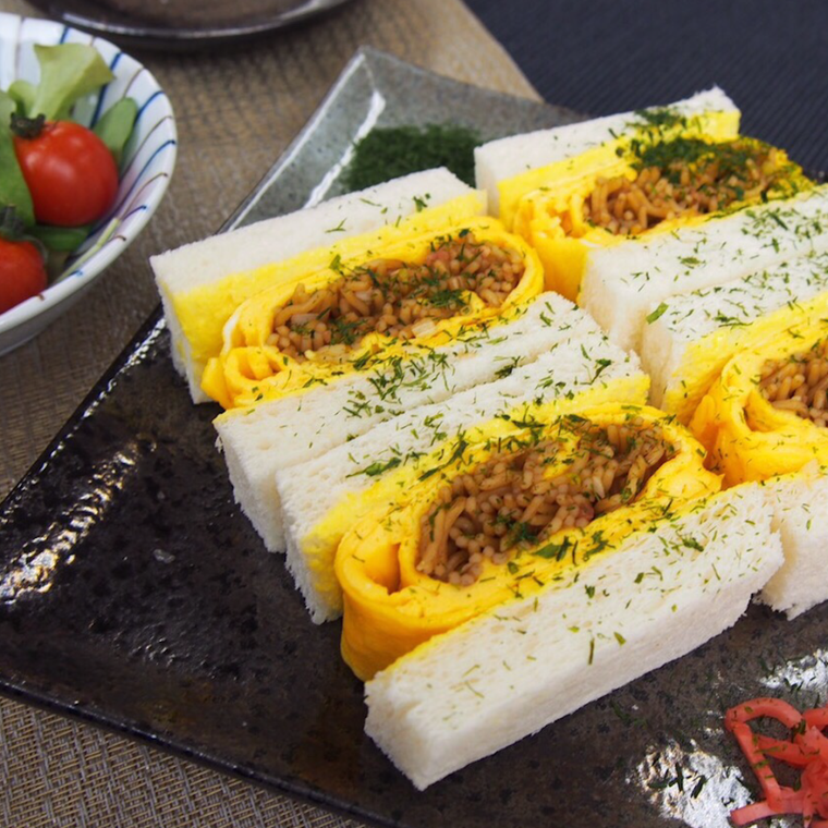 黒い皿に盛られた、焼きそば玉子サンド