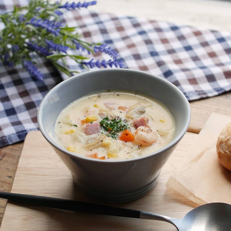 器に盛りつけられたコーンクリームチャウダーにスプーンとパンが添えられている