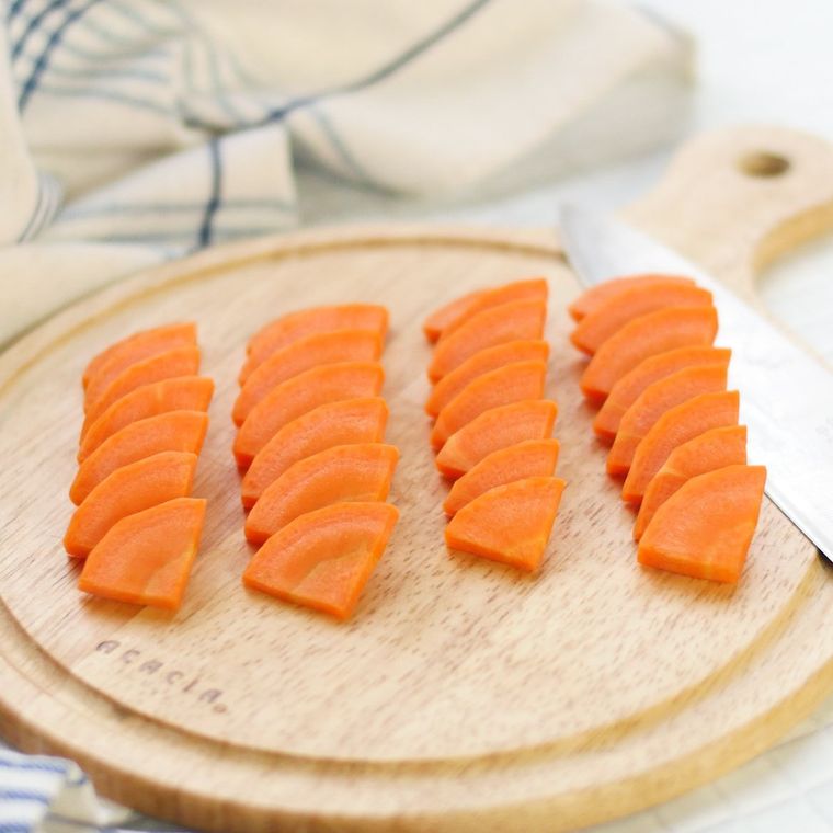丸いカッティングボードの上でいちょう切りにされたにんじん