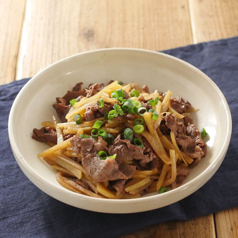 白い深皿に盛りつけられた、じゃがいもと牛肉のバターしょうゆ炒め