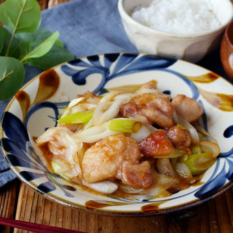 青い模様入りの白い皿に盛られた、鶏もも肉と長ねぎのポン酢しょうゆ炒め