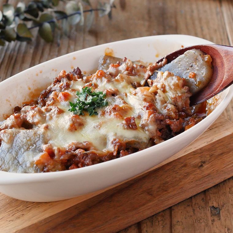 白い耐熱皿に入ったこんにゃくミートグラタンを、スプーンですくっている様子