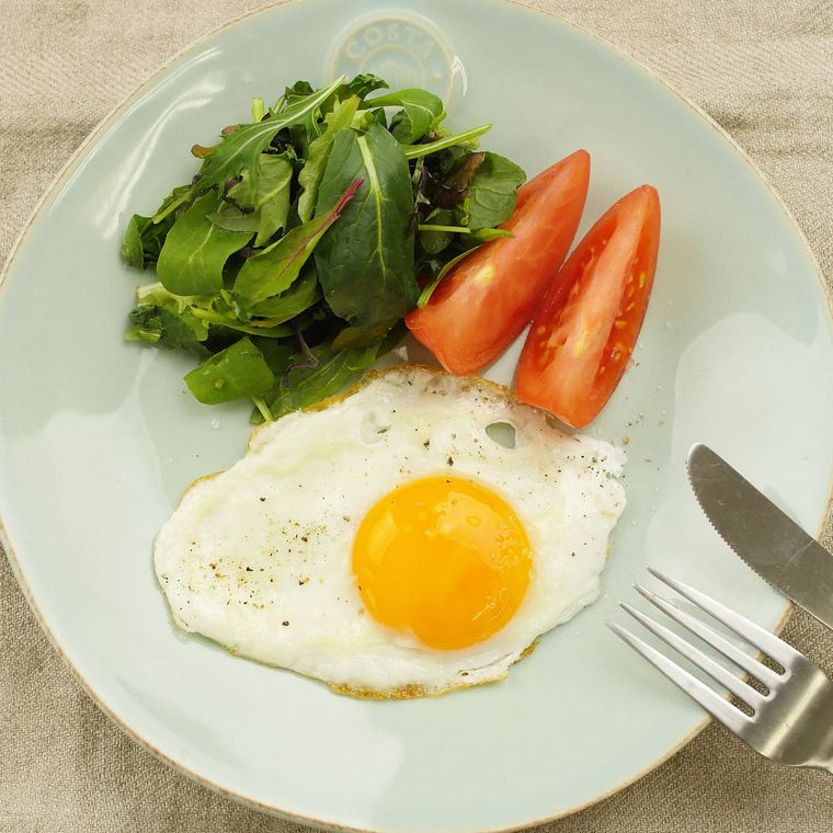 薄いブルーグレーの皿に盛り付けられている半熟とろとろ目玉焼きとサラダ
