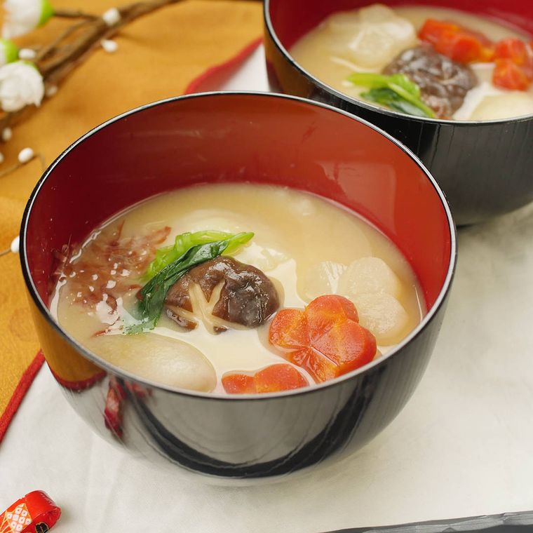 塗りのお椀に盛りつけられた丸餅とにんじん、大根などの白みそ雑煮