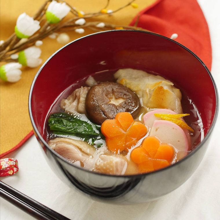 塗りのお椀に盛りつけられた切り餅と鶏もも肉、野菜のすまし雑煮