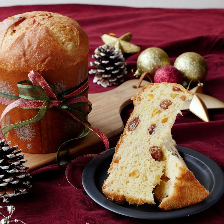 木製のボードにのせたパネトーネと、カットして黒い皿にのせたパネトーネ