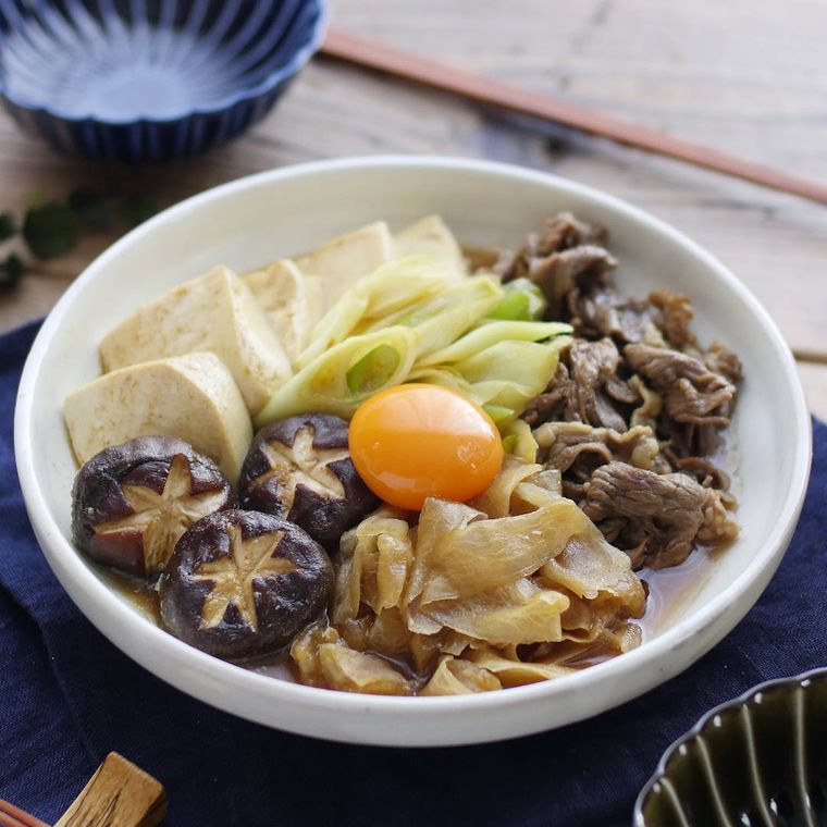 白い深皿に盛りつけられた牛肉と大根、豆腐などのカレー煮込み