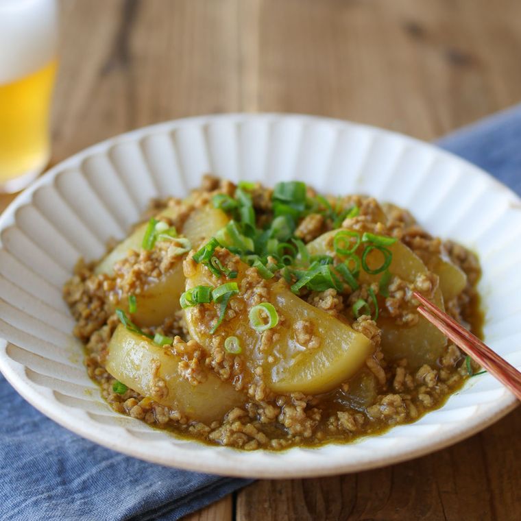 花びら模様の白い皿に盛りつけられた大根のカレーそぼろあん