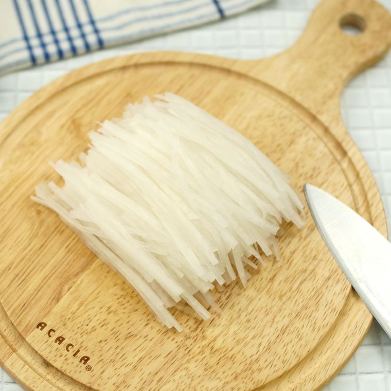 丸い木製のまな板にのった千切り大根