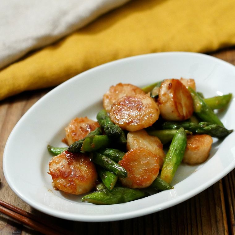 白い皿に盛りつけられた貝柱とアスパラガスのしょうゆ炒め