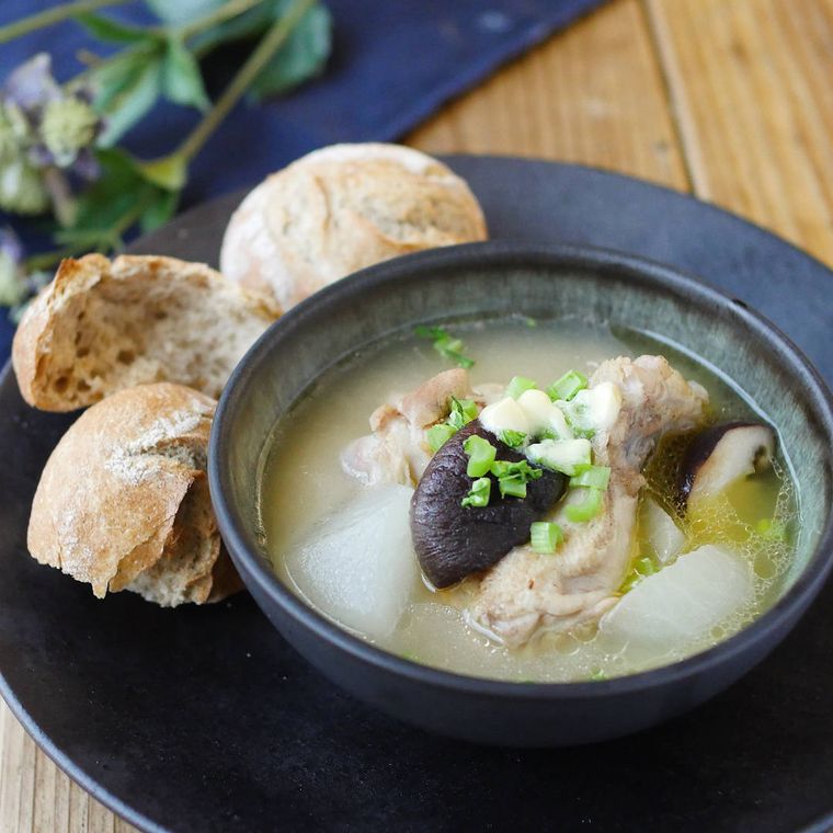 黒い皿に入った鶏手羽元と大根のほっこり白味噌スープ