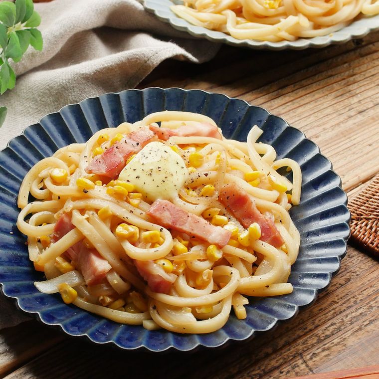 紺色の皿に盛り付けられているバターしょうゆのとうもろこしうどん