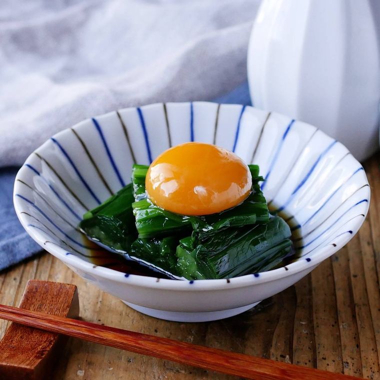 青い線が入った器に盛られたニラのおひたしと卵黄のトッピング