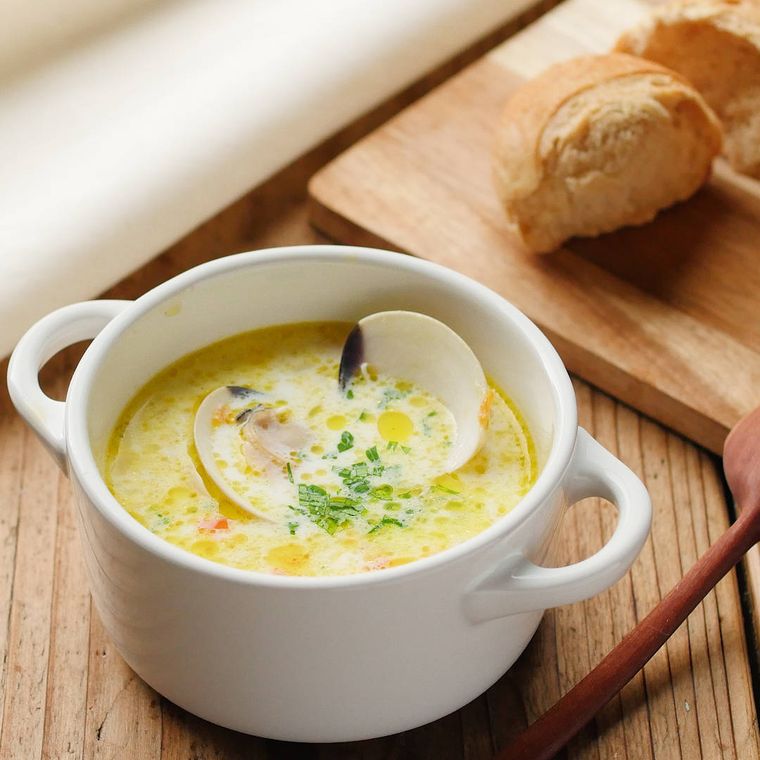 両手つきマグカップに盛りつけられたはまぐりの白みそクリームスープ