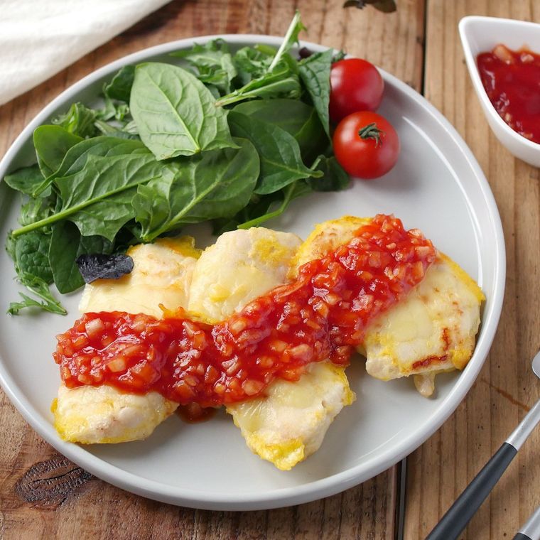 トマトソースがけ鶏むね肉のチーズピカタとサラダが盛られている白い皿