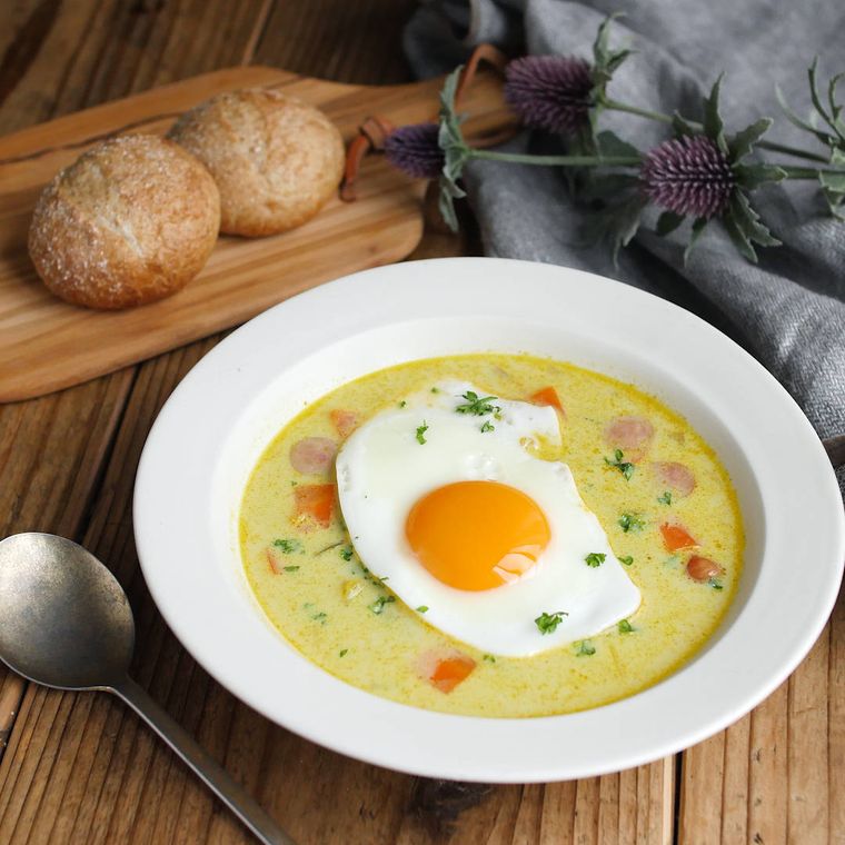 白いスープ皿に入れ目玉焼きをのせた豆乳カレースープ