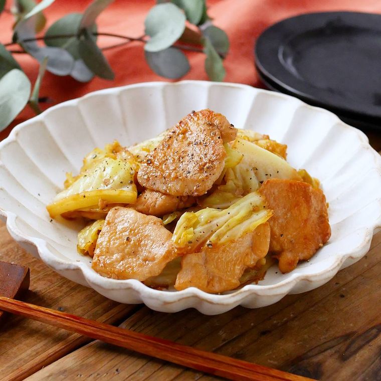 白い皿に盛り付けられている鶏胸肉とキャベツのガリバタ炒め